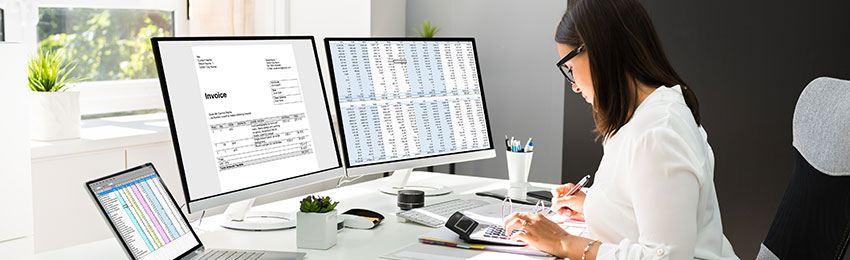 An accountant reviews accounting documents and makes calculations at her desk