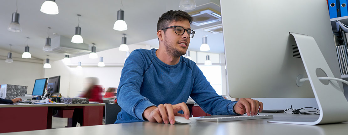 A graphic designer uses Adobe software on his desktop computer