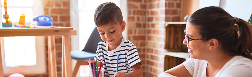 Adult woman working with child who is painting