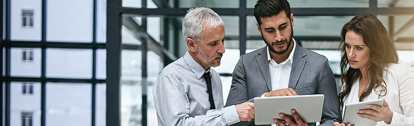 Three managers review business documents on their tablets