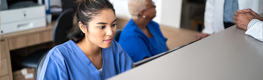 A medical office assistant works at a desk