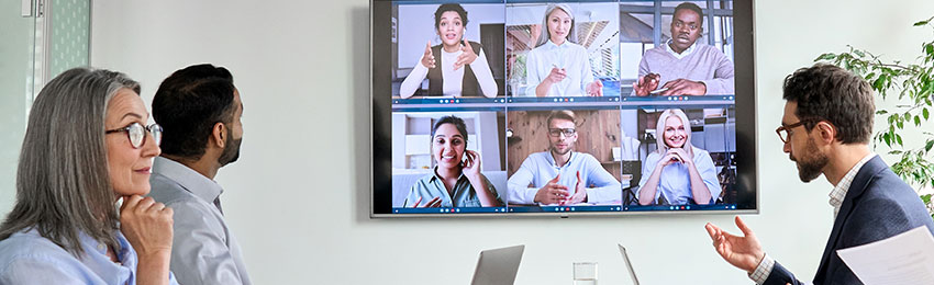 Office professionals participate in a hybrid (in-person and virtual) meeting