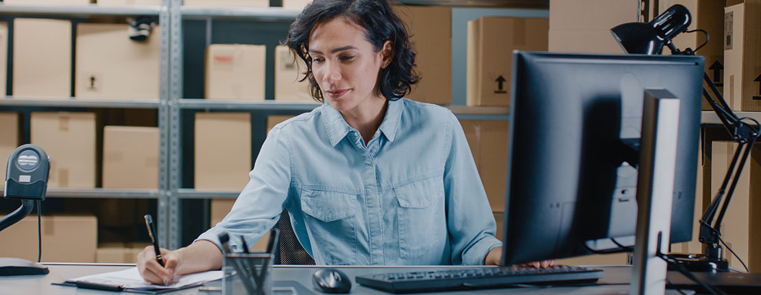 Female Inventory Manager Works on a Computer while Sitting at Her Desk