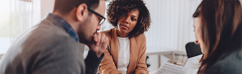 A professional explaining a contract to two people.