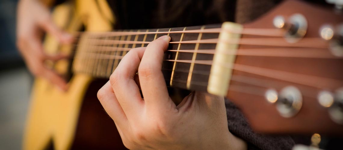 Person holding a chord position on the guitar