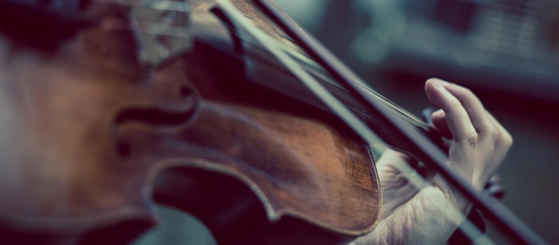  A violin, bow and hand placed in position on the neck of the instrument