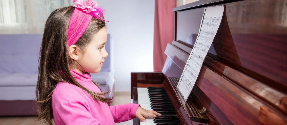 Young girl sitting at the piano in front of sheet music preparing to play