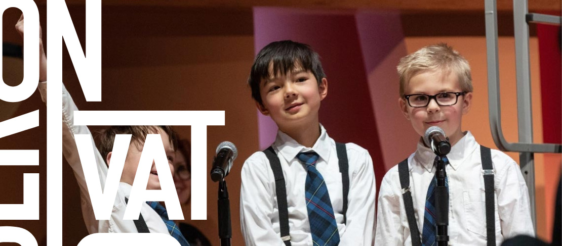 Three young boys standing behind microphones on stage