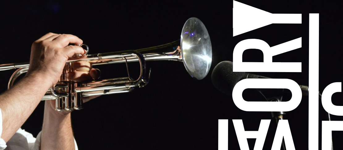 Hands playing a trumpet into a microphone.
